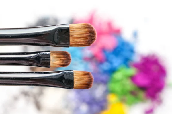 Pincéis de maquiagem profissional em sombras coloridas esmagadas — Fotografia de Stock