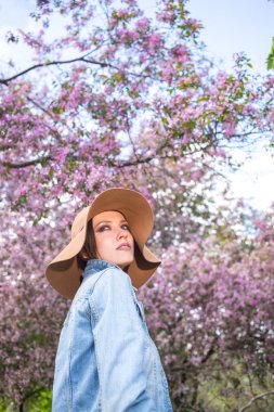 Pembe ağaçlar çiçekli bir parkta genç kadın