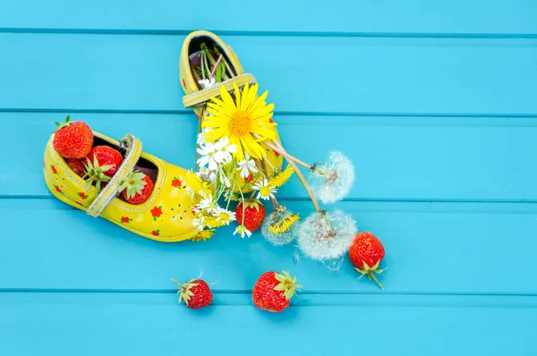 Летний фон с клубникой и крохотной детской обувью — стоковое фото