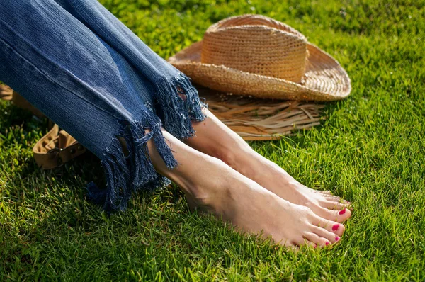 Barfota kvinnliga ben sitter i gröngräset — Stockfoto
