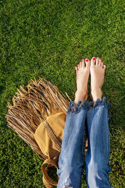 Barefoot vrouwelijke benen zitten in het gras — Stockfoto