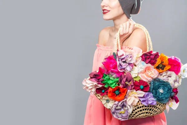 Красивая женщина в розовом платье держа цветочный мешок изолирован над серым — стоковое фото