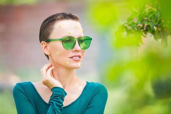 Krásný přírodní model nosí sluneční brýle a s květy heřmánku — Stock fotografie