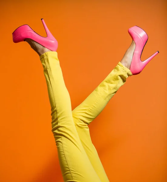 Female legs wearing high heels over bright orange background — Stock Photo, Image