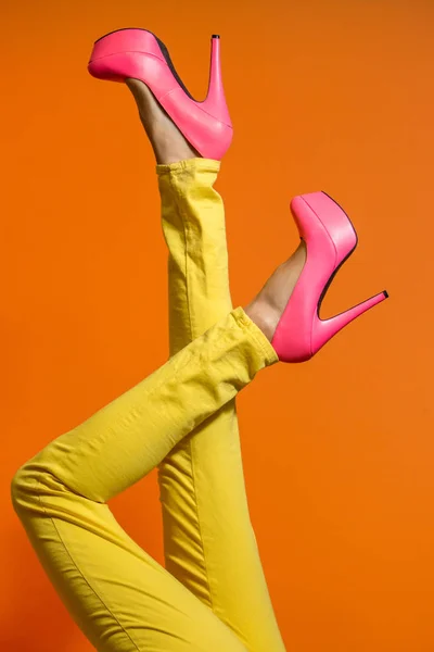 Female legs wearing high heels over bright orange background — Stock Photo, Image