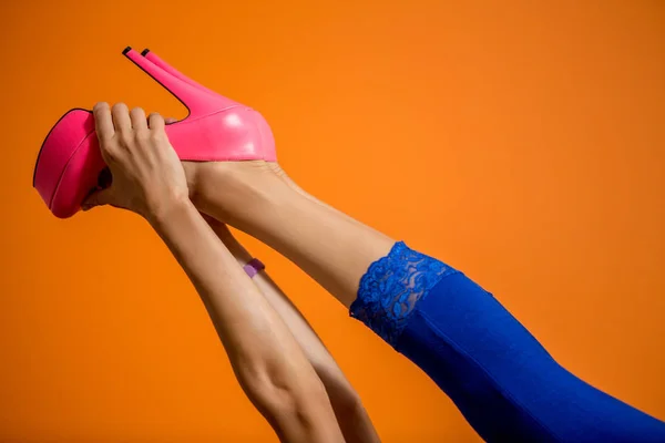 Parlak turuncu arka plan üzerinde yüksek topuklu giyen kadın bacakları — Stok fotoğraf