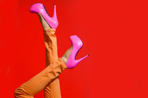 Female legs wearing high heels over bright red background