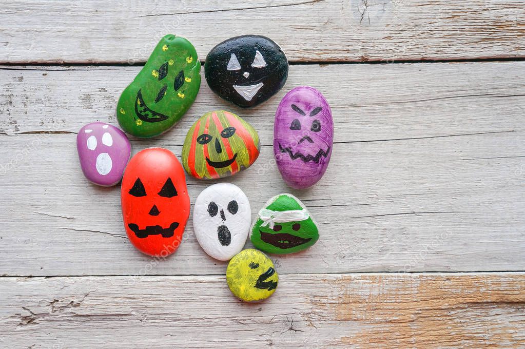 Halloween background with funny painted stones like ghosts, top view