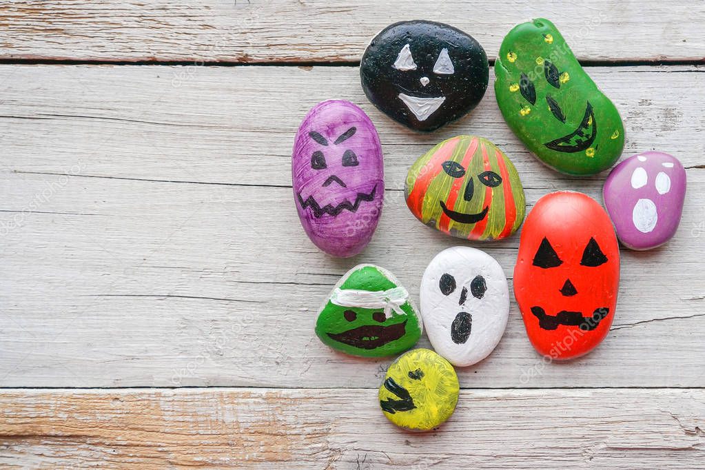Halloween background with funny painted stones like ghosts, top view