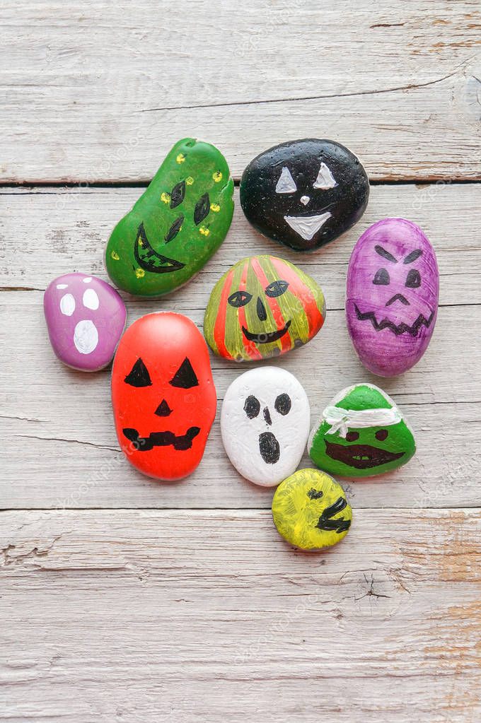 Halloween background with funny painted stones like ghosts, top view