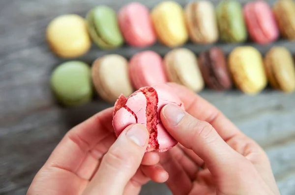 Mãos Femininas Segurando Macaroon Rachado Sobre Fundo Madeira Com Muitos — Fotografia de Stock