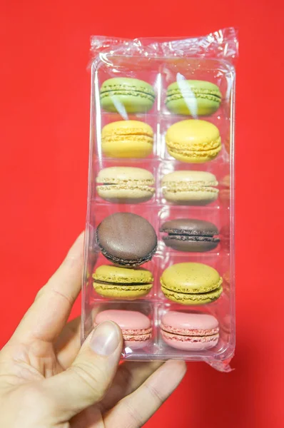 Mão Masculina Segurando Uma Caixa Com Macaroons Sobre Fundo Vermelho — Fotografia de Stock