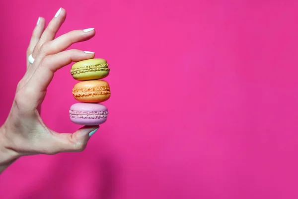 Mano Femenina Sostiene Colorido Macarrón Sobre Fondo Rosa Brillante —  Fotos de Stock