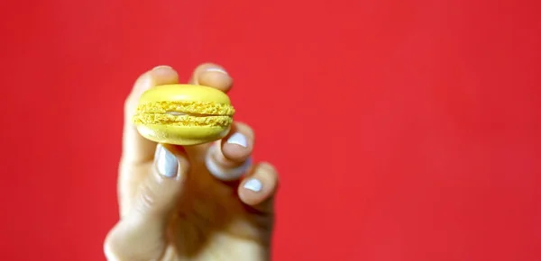 女性の手を掌握赤黄色のレモンのマカロン — ストック写真