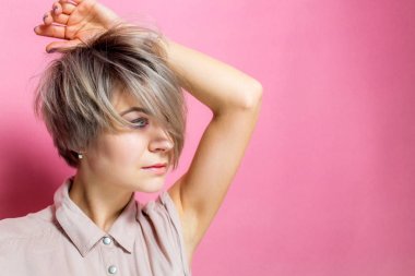 İhale gülümseme pembe arka plan üzerinde pastel renklerle gündelik kıyafeti giymiş olan romantik kadın portresi