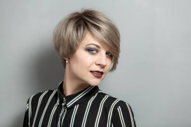 gri arka plan üzerinde kısa saçlı güzel genç kadın moda