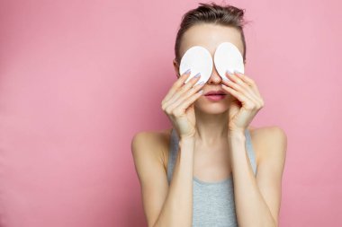 Sağlıklı taze kız ile pamuk yastık yüzü makyaj kaldırılıyor. Güzellik kadını yüzü ile pamuk çubukla yastık pembe arka plan üzerinde izole temizlik. Cilt bakım ve güzellik kavramı