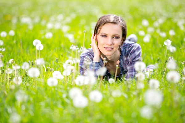 美しい女性のタンポポ フィールドを楽しんで 花の草原に横たわる 種子を離れた吹きます 楽しい時を過す屋外 春の草の上でリラックスしたかわいい女の子 緑の自然に幸せな春の女性 — ストック写真