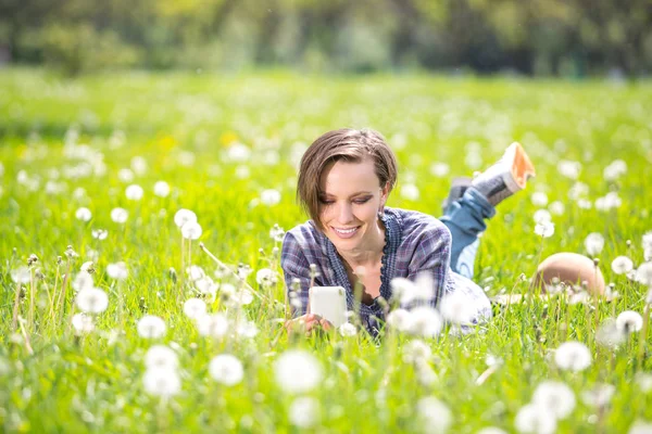 Jonge Vrouw Met Behulp Van Mobiele Telefoon Een Weide Voorjaar — Stockfoto