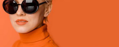 Turuncu arka planda güneş gözlüğü takan kadın modelin güzel portresi.