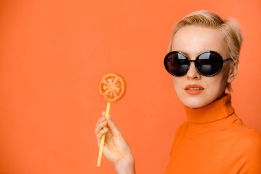 Moda güneş gözlüğü takan ve elinde bir dilim domates tutan kadın modelin güzel portresi.