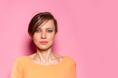 Pembe arka planda kameraya bakan güzel, neşeli bir kızın portresi.