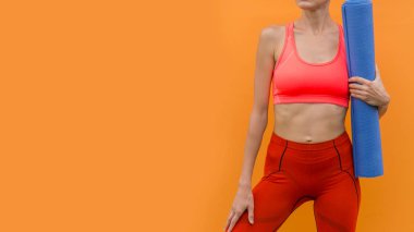 Yoga minderli sportif yoga kızı sarı turuncu arka planda izole edilmiş.