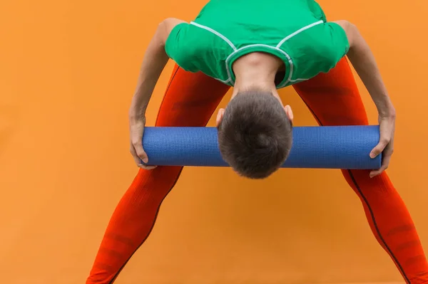 Sporty yoga girl with yoga mat isolated over yellow orange background
