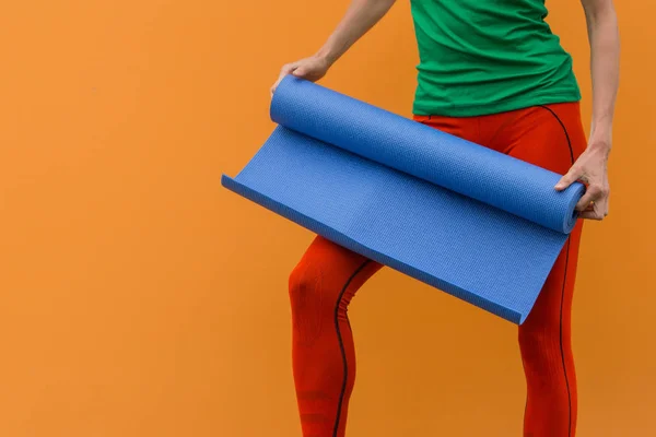 Sporty yoga girl with yoga mat isolated over yellow orange background