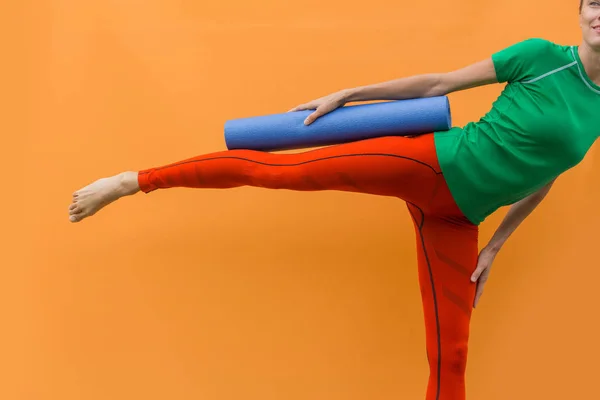 Sporty yoga girl with yoga mat isolated over yellow orange background