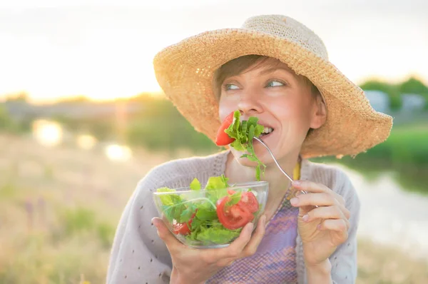 美丽的高加索妇女吃沙拉在绿色自然背景 — 图库照片