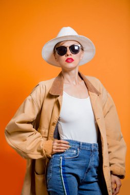 Büyük beden giyimli moda kadını. Güneş gözlüğü, şapka, kot pantolon ve büyük beden erkek arkadaş ceketi giyen bir kadın. Seksi işçi.