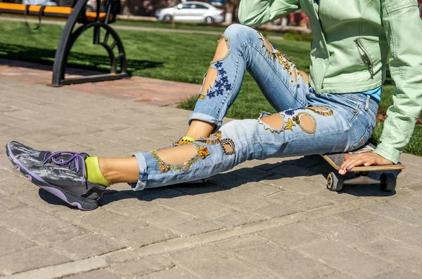 Street fashion, young woman in torn jeans with decor, copy space