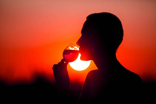 Woman with a cocktail over suset sky in red colors