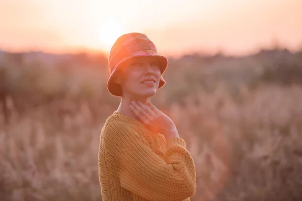 美丽的年轻女子穿着针织毛衣和毡帽享受温暖的天在公园 — 图库照片