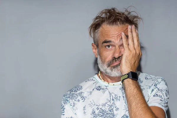 Confused man with funny messy hair. Indoor portrait of handsome man with grey beard and hair