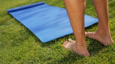 Adam güneşli bir çayırda yoga antrenmanına gidiyor. Yoga bacak konsepti
