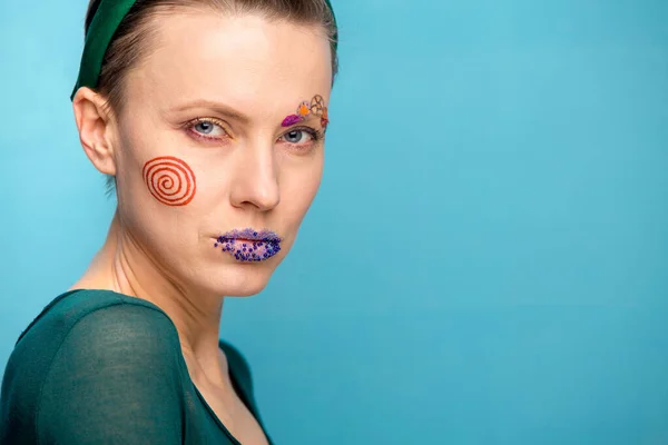 Beautiful woman with unusual makeup over blue background