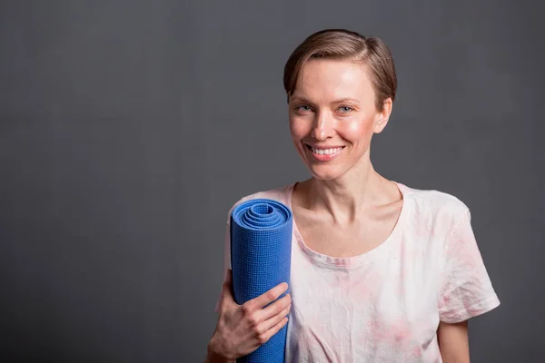 Sporty yoga girl with yoga mat isolated over grey background