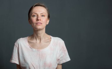 Kısa saçlı, mutlu, genç bir kadın. Gri arka planda doğal bir makyaj. Güzel esmer bir kadının kapalı bir portresi.