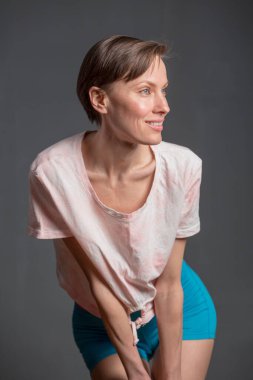  Kısa saçlı, mutlu, genç bir kadın. Gri arka planda doğal bir makyaj. Güzel esmer bir kadının kapalı portresi, kopyalama alanı.