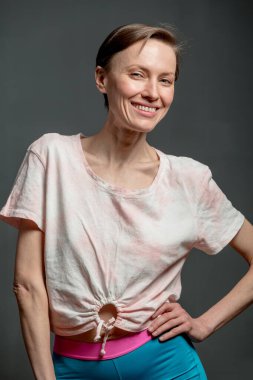 Kısa saçlı, mutlu, genç bir kadın. Gri arka planda doğal bir makyaj. Güzel esmer bir kadının kapalı bir portresi.