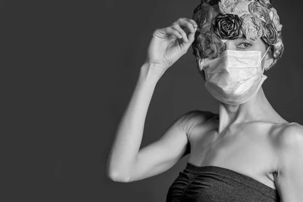 戴着医疗面罩的女人戴着灰色背景的人造花冠 复制空间 — 图库照片