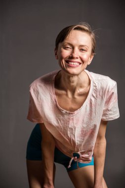 Kısa saçlı, mutlu, genç bir kadın. Gri arka planda doğal bir makyaj. Güzel esmer bir kadının kapalı portresi, kopyalama alanı.