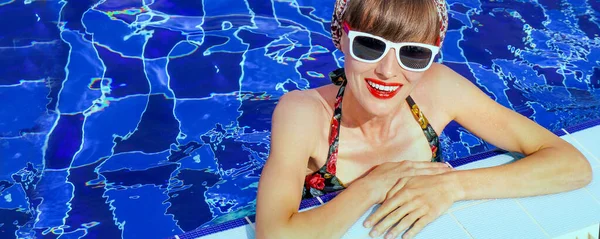 Stylish portrait of pretty young woman posing in the swimming pool.  Swimsuit, sunglasses, retro look, outdoor fashion portrait elegant woman relaxing