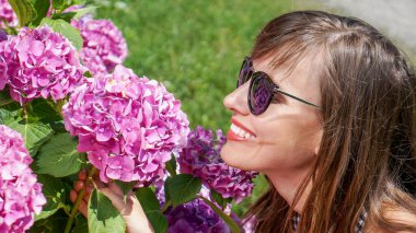 Karantina sonrası güzel yaz çiçekleriyle fotoğraf çeken genç bir kadın.