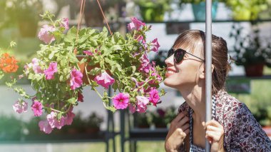  Yeşil parkta, yaz elbisesinde oturan güzel bir kadın. Çiçekli hidragea çalılarının üzerinde.