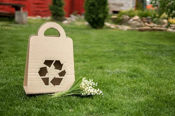 Papperspåse Med Återvinningsskylt Och Blommor Över Grönt Gräs Bakgrund — Stockfoto