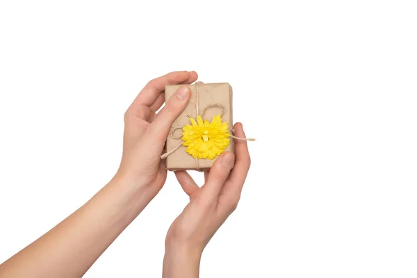 Жіночі руки тримають подарункову коробку з жовтою квіткою на білому тлі . — стокове фото