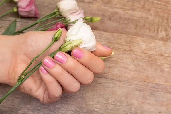 Kobieta ręka z różowym projektu paznokci gospodarstwa biały kwiat — Zdjęcie stockowe